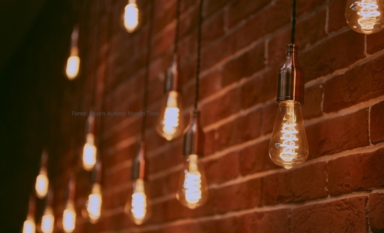 Diverse lampadine che illuminano un ambiente rustico, a simboleggiare l'energia elettrica oggetto del nuovo decreto governativo di febbraio 2026. L'articolo approfondisce il contributo da 115 euro per le famiglie vulnerabili e le nuove soglie ISEE per i bonus sociali.